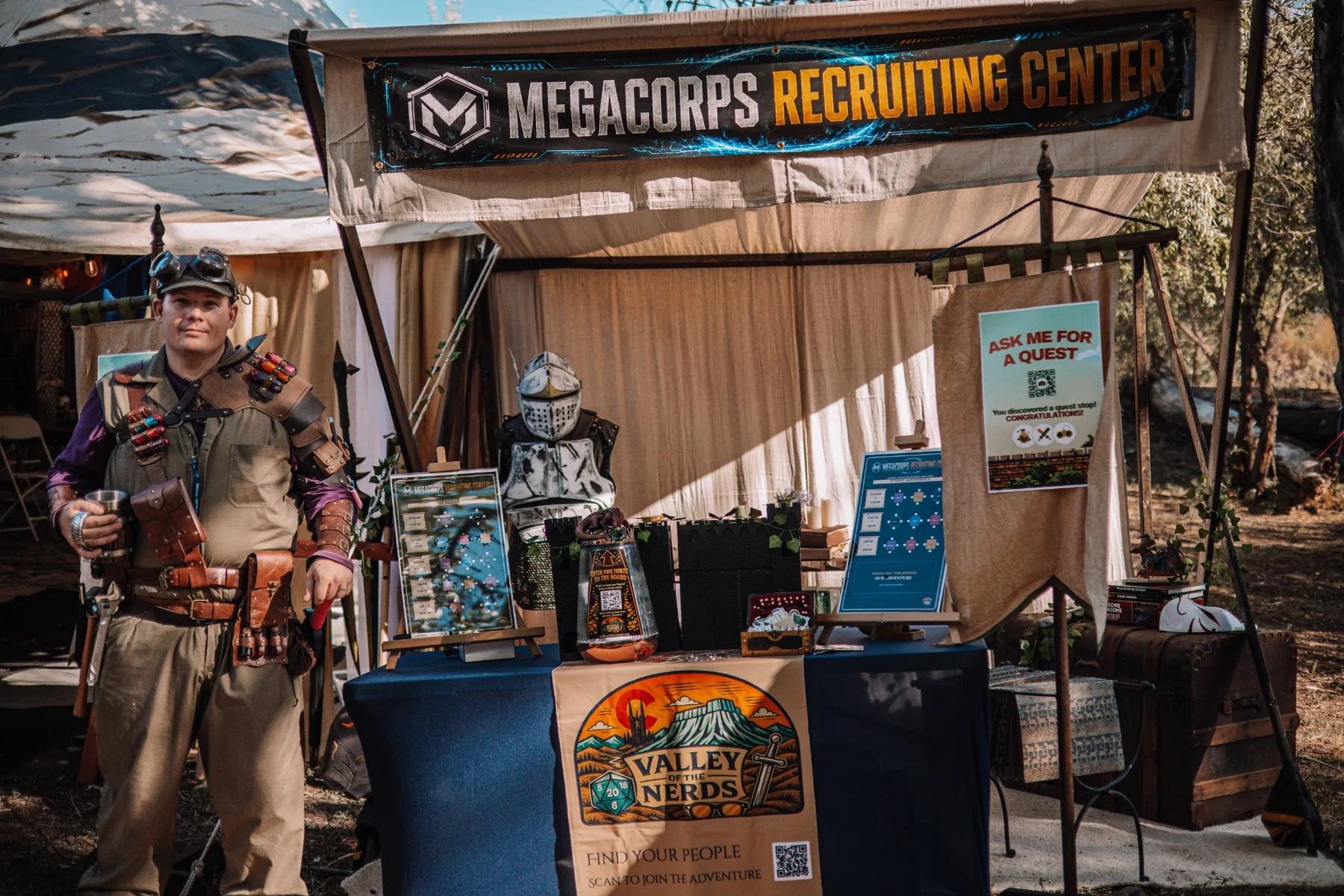 The Megacorps Recruitment Center tent with costumed staff, props, schedules, and Valley of the Nerds signage.