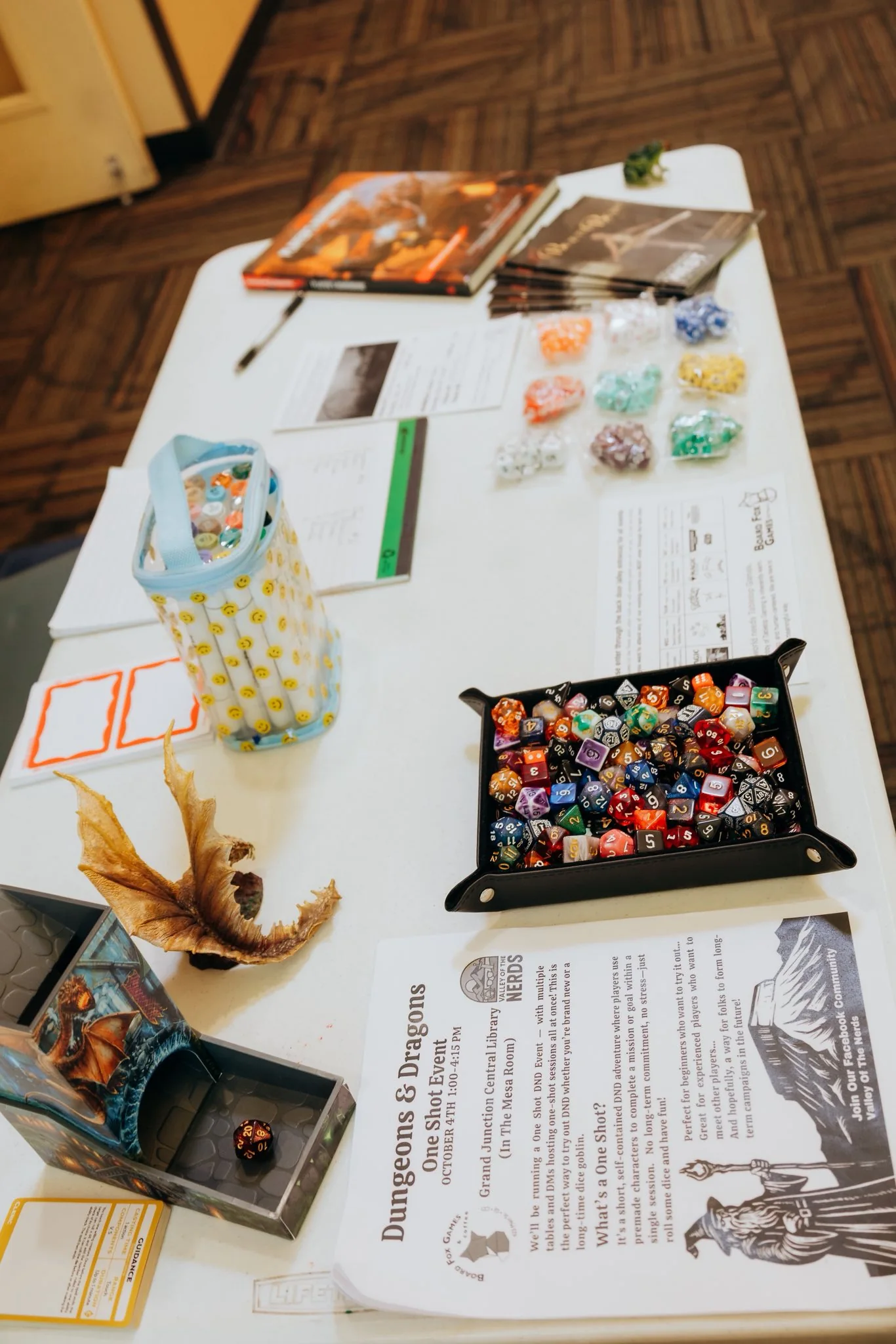 A table arranged with dice, handouts, and supplies for a one-shot event.
