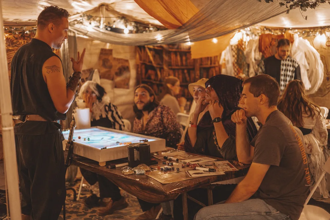 Community members following a tabletop adventure together, with game materials spread across the table.